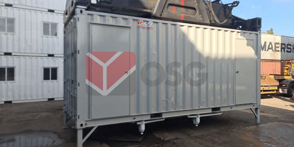 Metal shipping container on a worksite with equipment nearby.