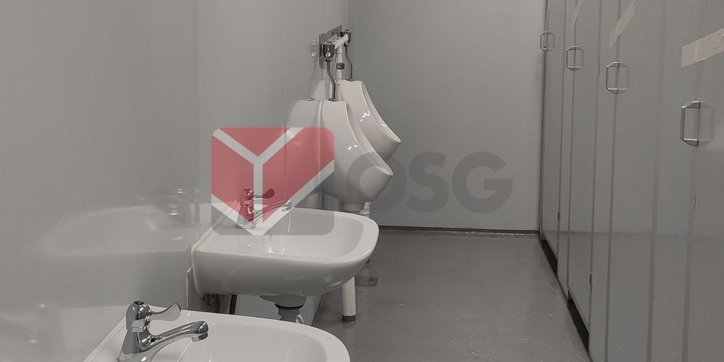 Restroom interior featuring sinks and urinals with gray walls.