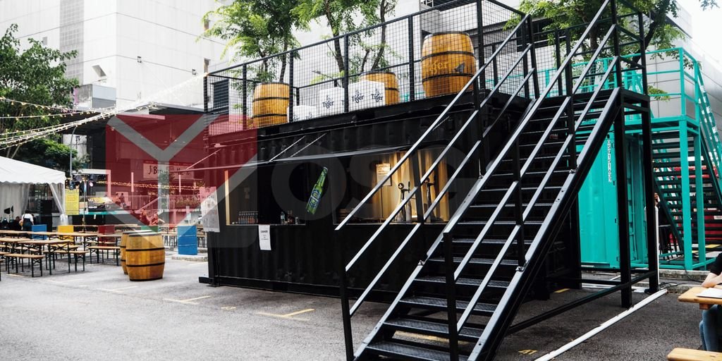 A modern shipping container structure with stairs and outdoor seating.