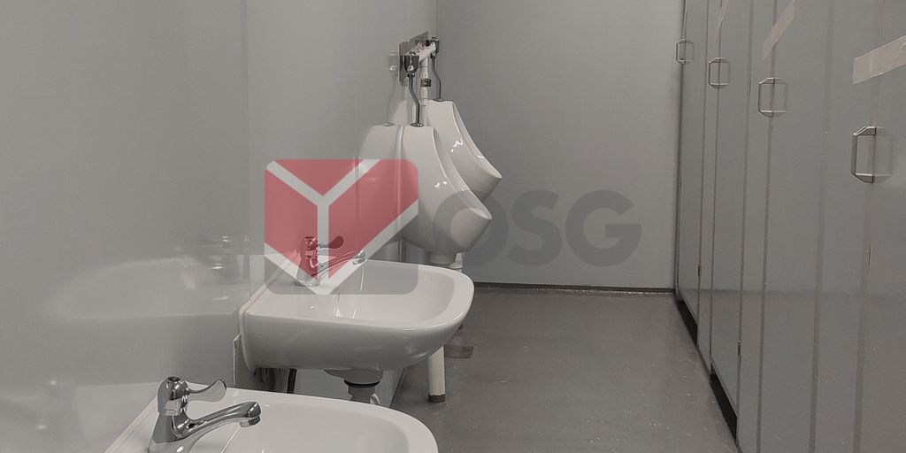 Restroom interior featuring sinks and urinals with gray walls.
