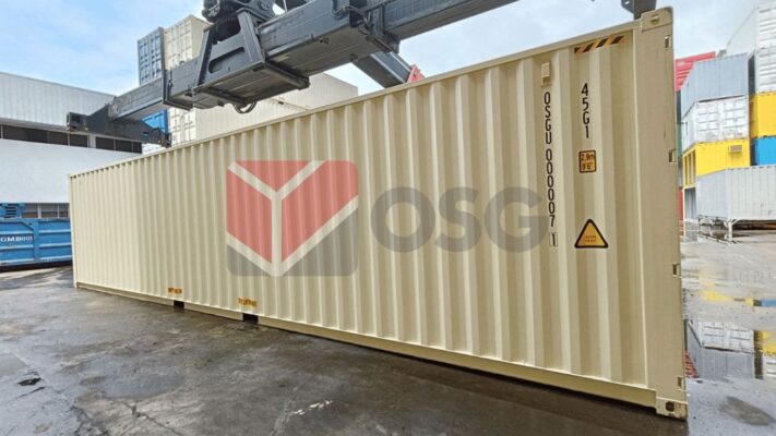 A large shipping container in a storage area, being lifted.