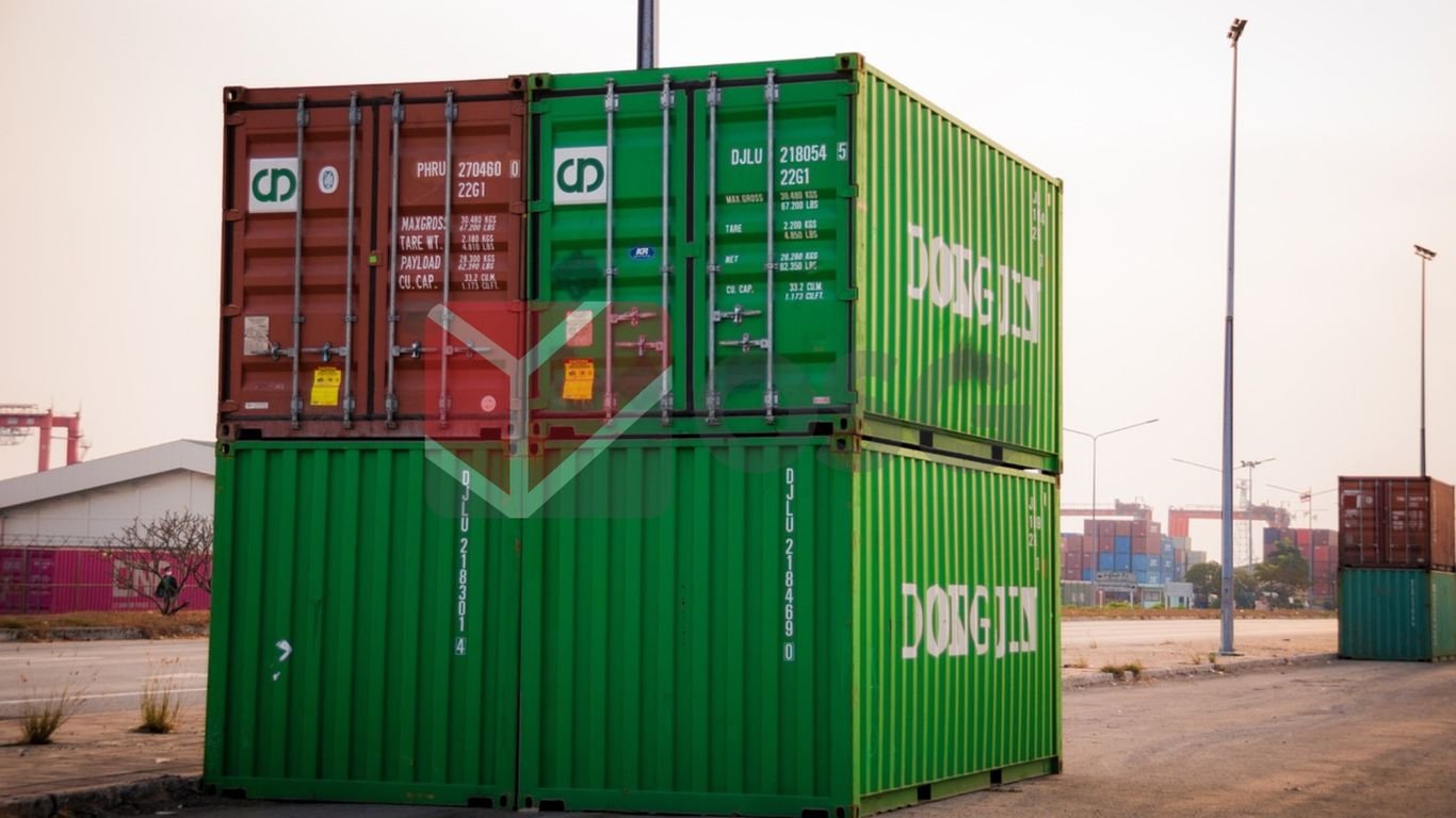 Stacked shipping containers in a port setting during sunset.