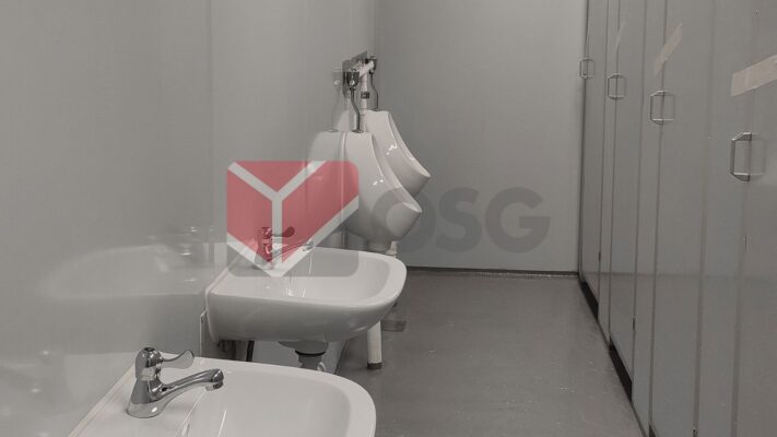 Restroom interior featuring sinks and urinals with gray walls.