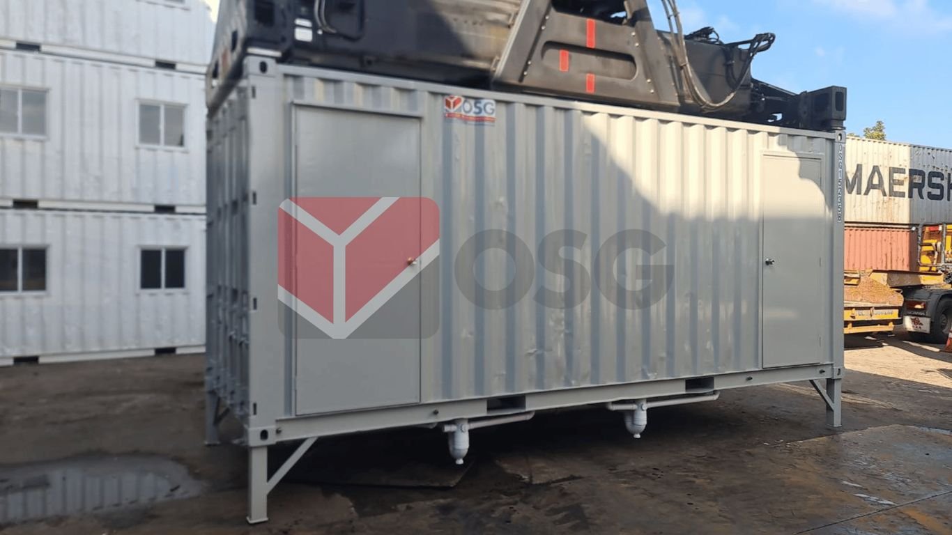 Metal shipping container on a worksite with equipment nearby.