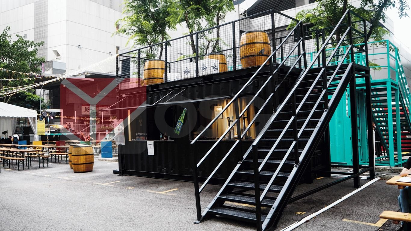 A modern shipping container structure with stairs and outdoor seating.