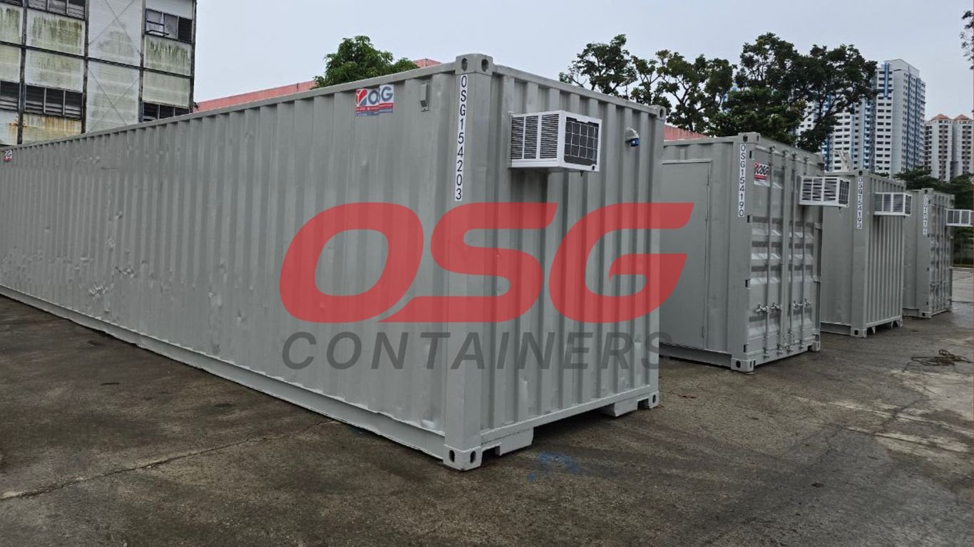 Several grey shipping containers with air conditioning units are lined up.