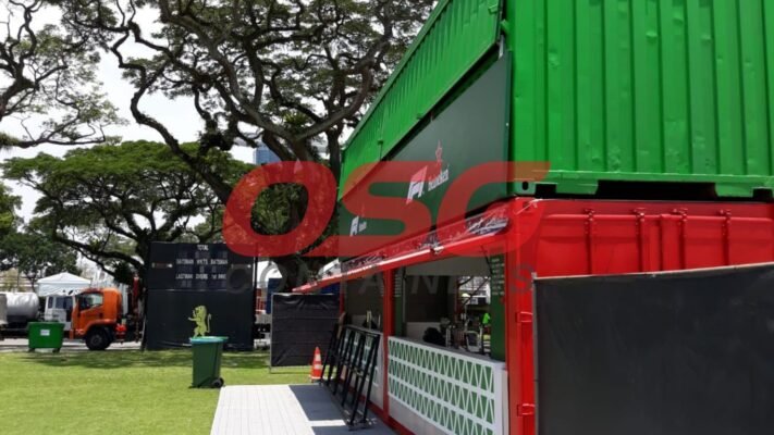 Two stacked shipping containers, one red and one green, with branding.