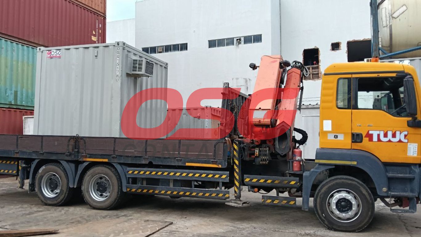 A crane truck is loading a shipping container onto its flatbed.