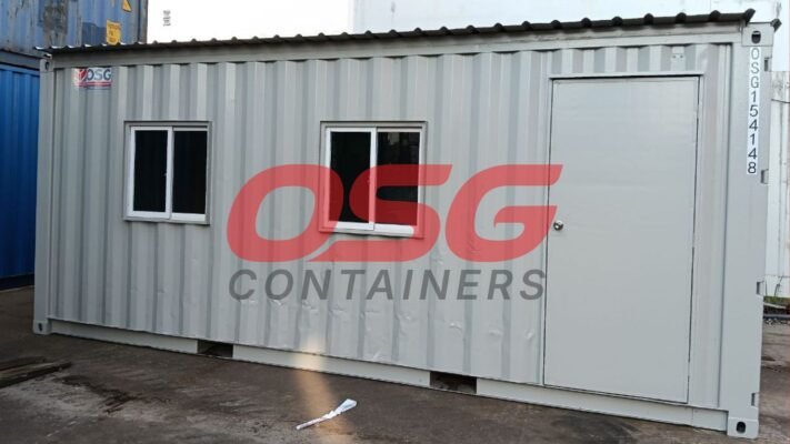 A grey shipping container modified into a small office or cabin.