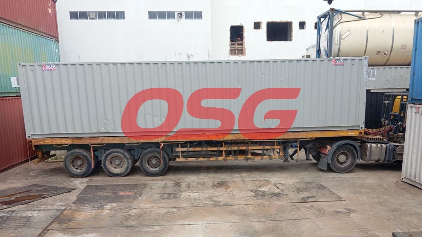 A large gray shipping container is loaded onto a truck.