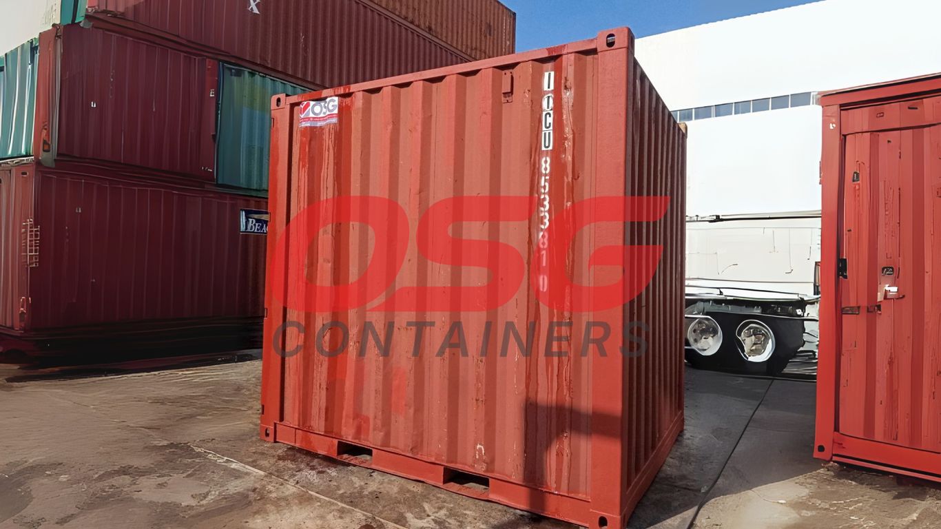 Red shipping containers stacked in a yard with a truck.