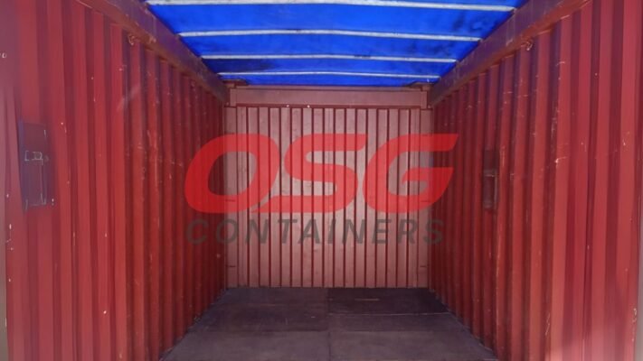Interior view of an empty red shipping container with a blue tarp.