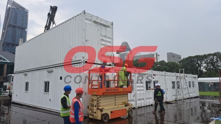 Workers install modular containers with a crane and lift.