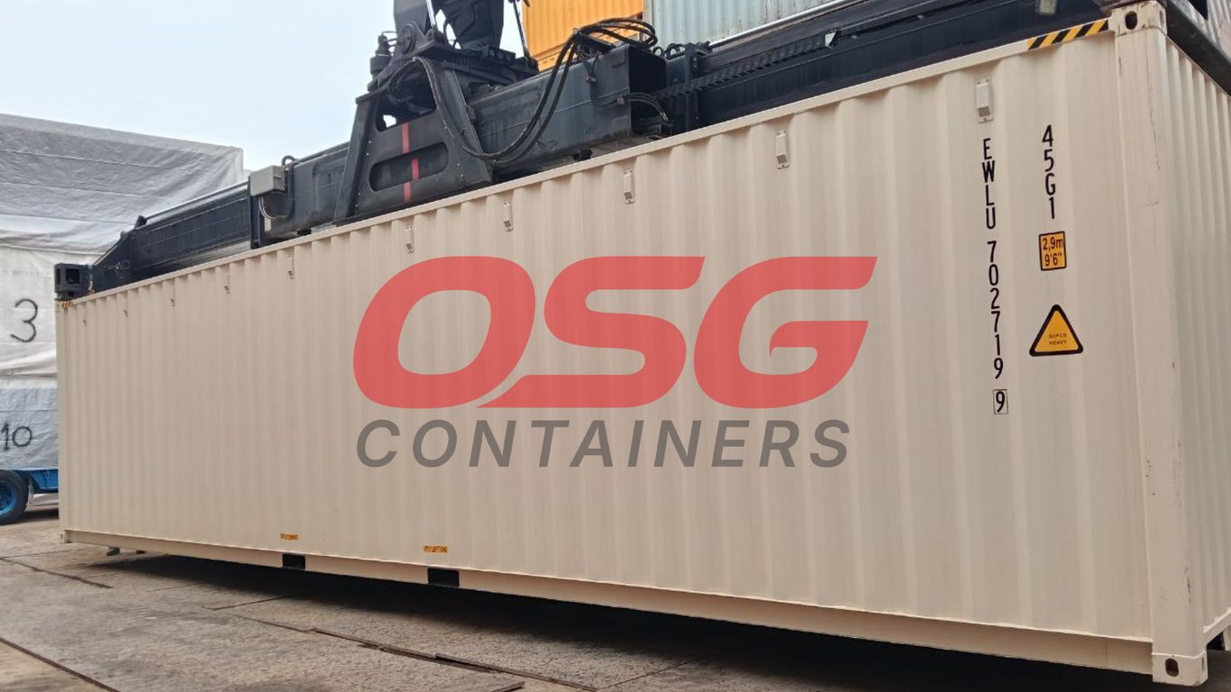 A crane lifts a large OSG container at a shipping yard.