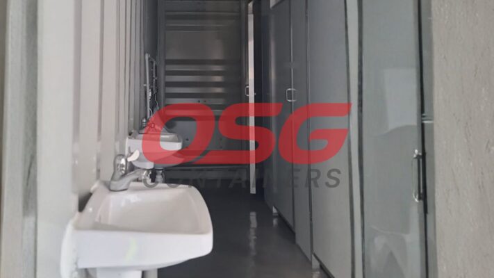 Interior view of a portable restroom facility with sinks and doors.