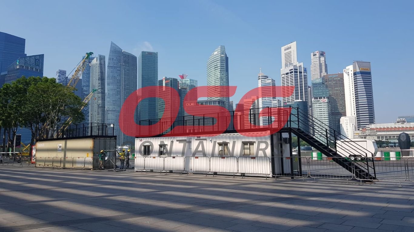 Shipping containers and modern buildings under a clear sky.
