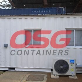 White shipping container office with windows and air conditioners.