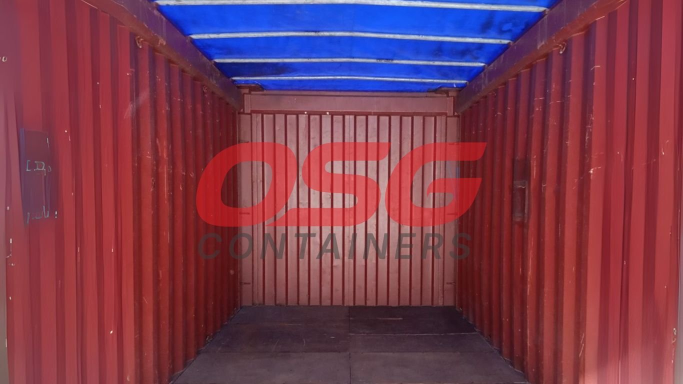 Interior view of an empty red shipping container with a blue tarp.