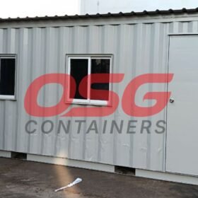 A grey shipping container modified into a small office or cabin.