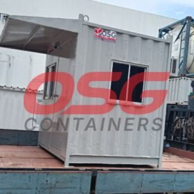 A portable guard house container is loaded onto a flatbed truck.