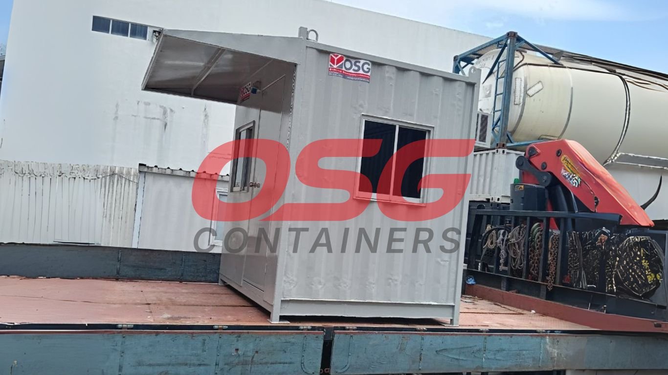 A portable guard house container is loaded onto a flatbed truck.