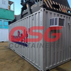 A shipping container with an air conditioner is being lifted.