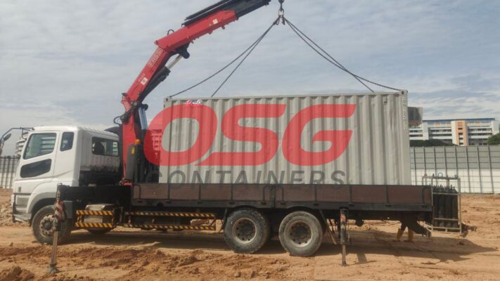 Crane truck loading a shipping container with OSG Containers logo.