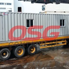 A container office unit is being loaded onto a truck.