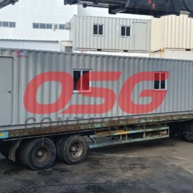 A container office is loaded onto a truck for transport.