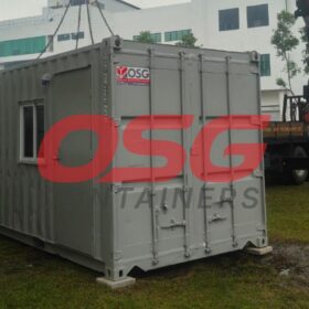 A crane is lifting a portable office container at a construction site.