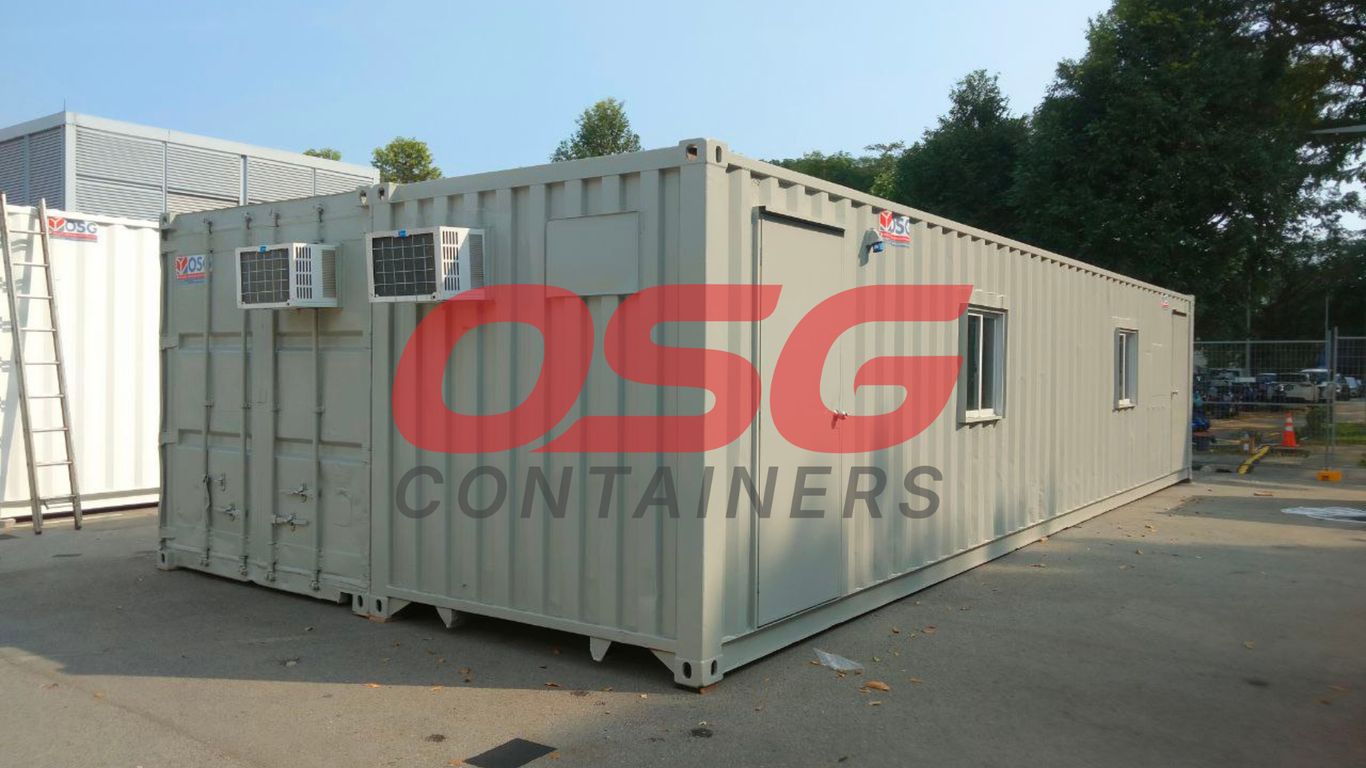 A long, light gray shipping container office with windows and air conditioners.