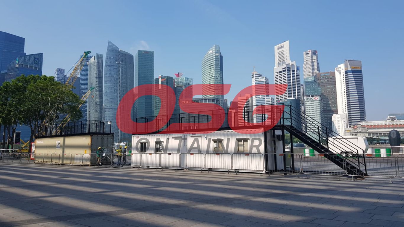 Shipping containers and modern buildings under a clear sky.