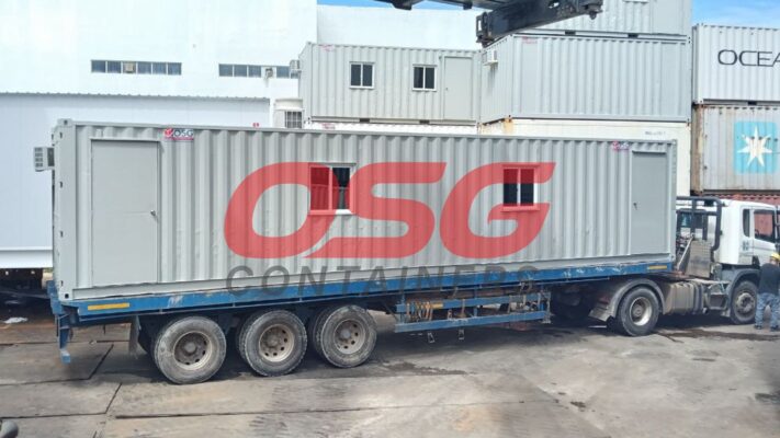 A long container is loaded onto a truck for transport.