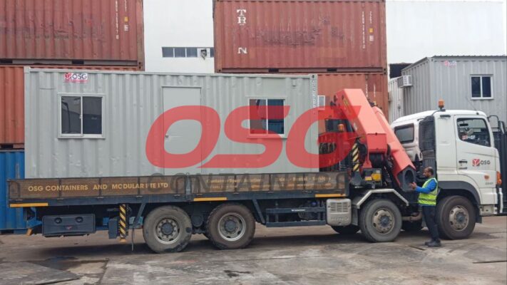 A truck with a crane is delivering a modular container.