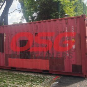 A weathered red shipping container with a large logo on its side.