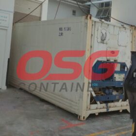 A refrigerated shipping container is parked next to a building.