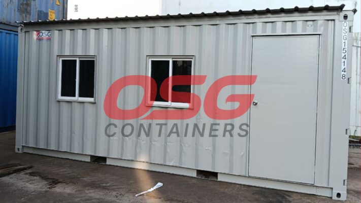 A grey shipping container modified into a small office or cabin.