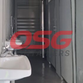 Interior view of a portable restroom facility with sinks and doors.