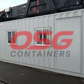 A light gray shipping container office with windows and a door.