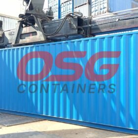 A large blue shipping container is being lifted by a crane.