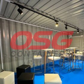 Modern bar setup inside a shipping container with seating.