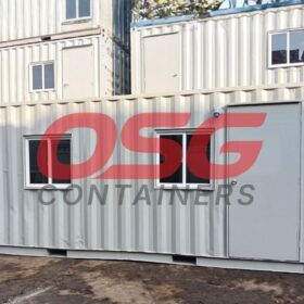 Stacked shipping containers with windows and doors, some with logos.