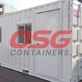 A white shipping container modified into a small office or room.