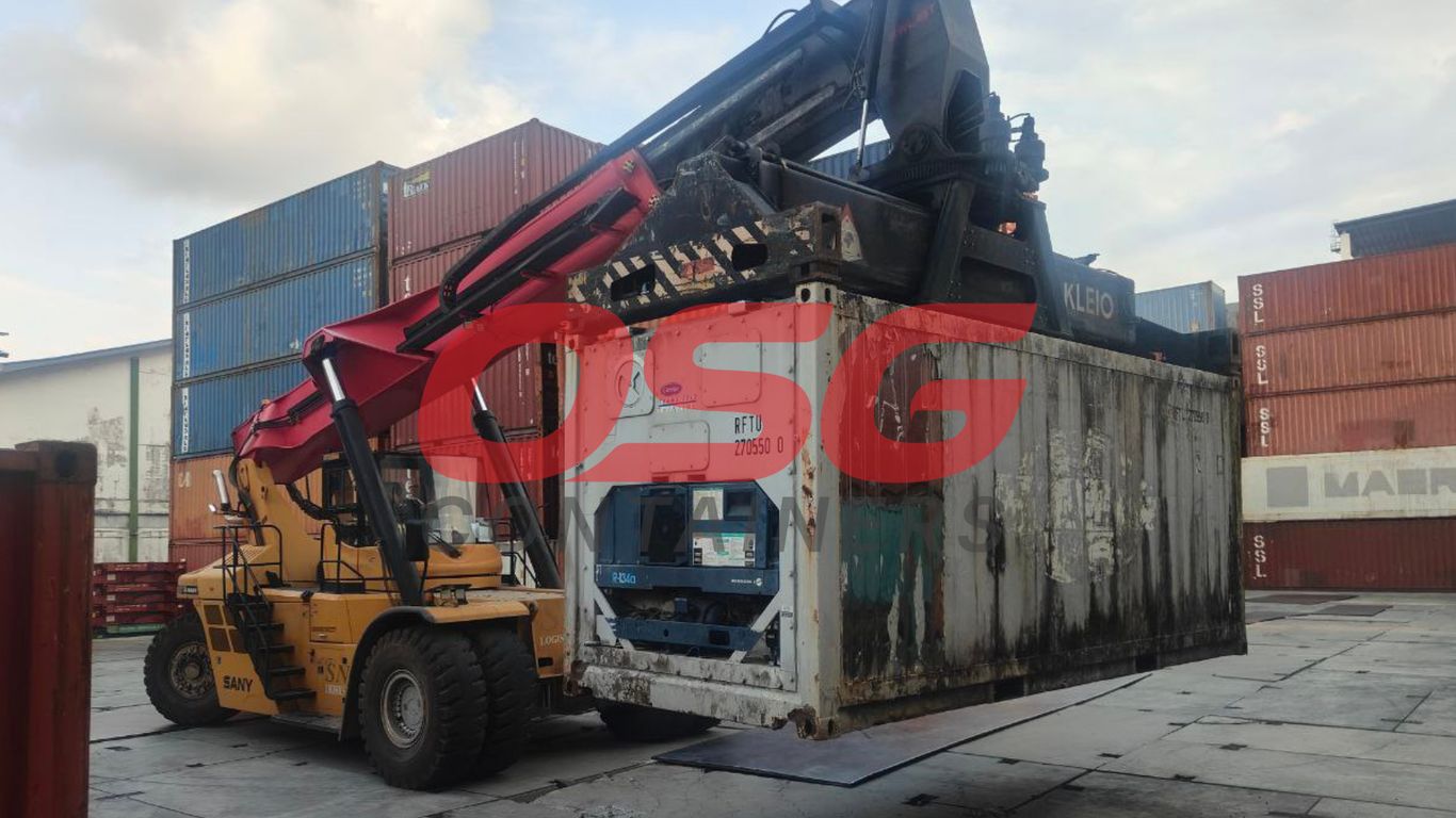 A forklift lifts a refrigerated shipping container at a port.