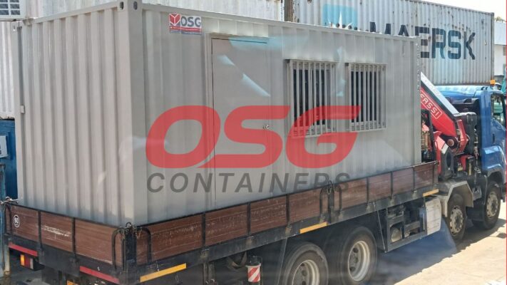 A portable container office is loaded onto a truck.