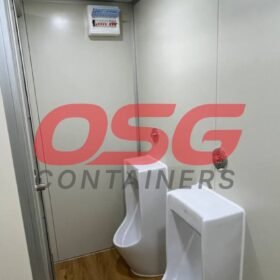 Interior of a portable restroom with two urinals and a control panel.