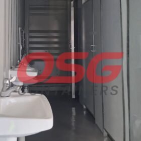 Interior view of a portable restroom facility with sinks and doors.