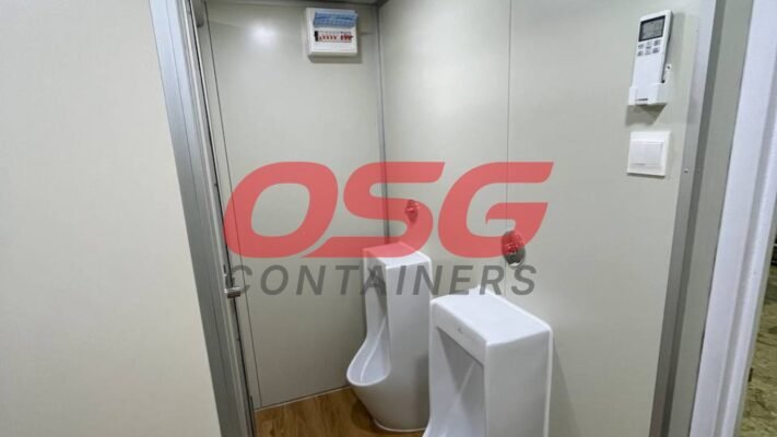 Interior of a portable restroom with two urinals and a control panel.