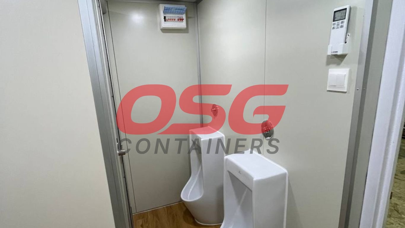 Interior of a portable restroom with two urinals and a control panel.