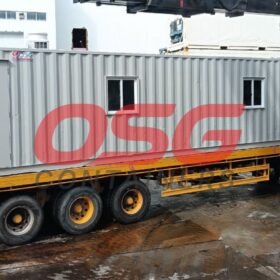 A container office unit is being loaded onto a truck.